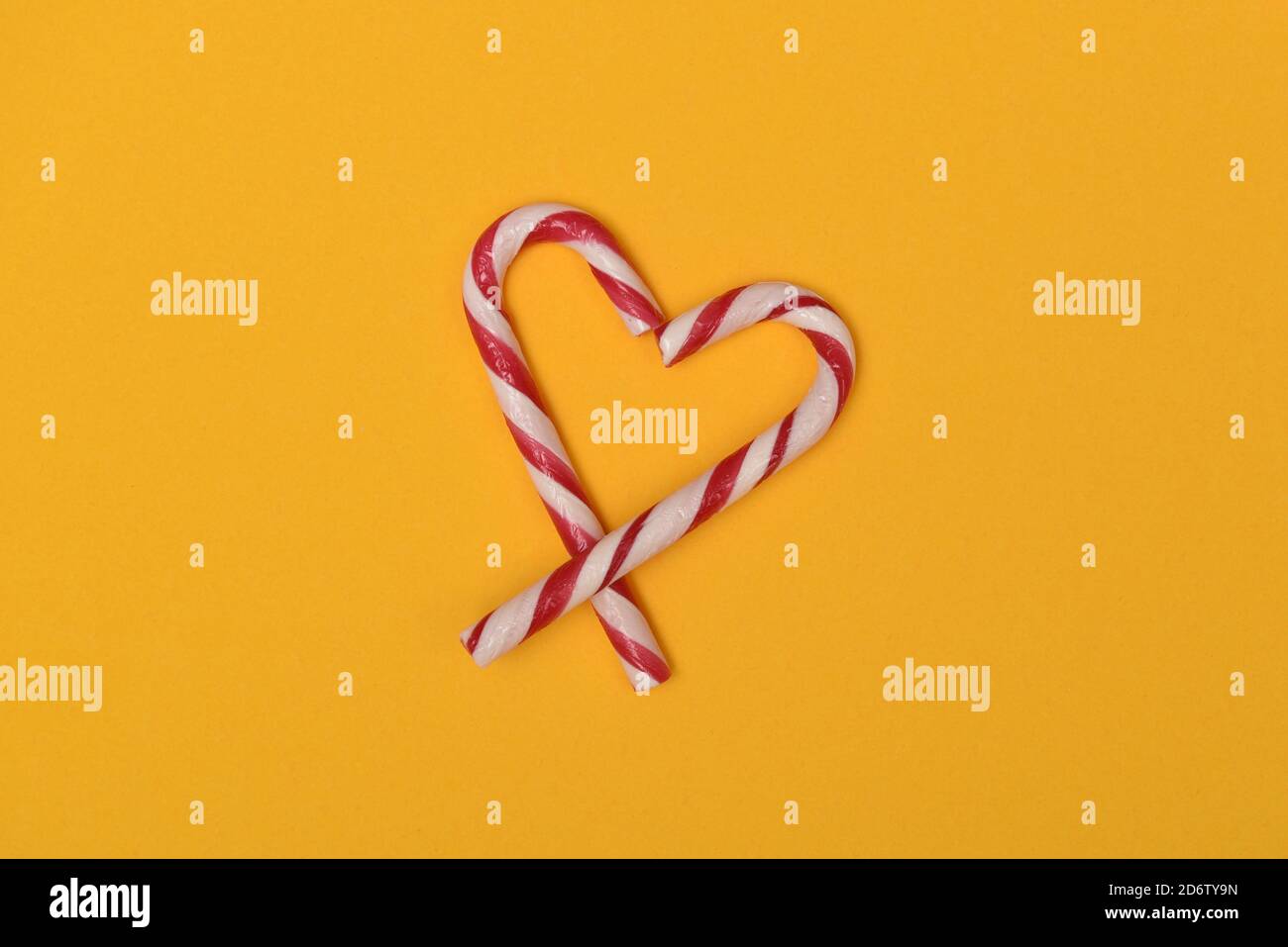 candy canes shaped as a heart isolated on a yellow background Stock Photo