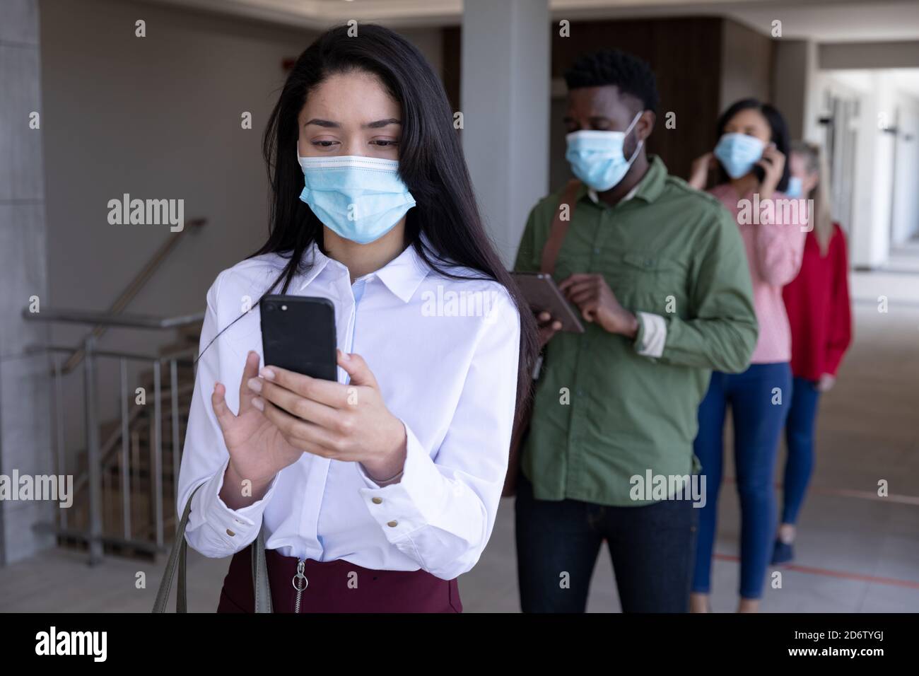 Group of people wearing face masks using smartphones while standing in queue Stock Photo