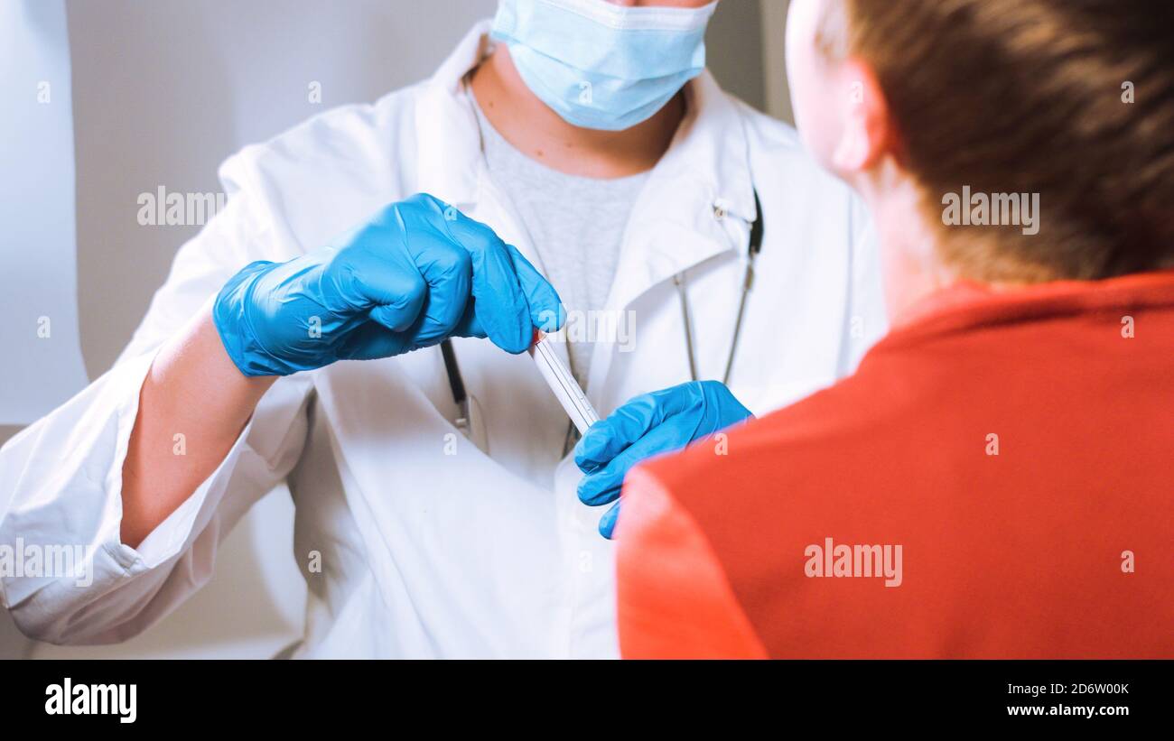 Doctor takes a cotton swab coronavirus test from child nose to analyse if postitve for covid-19. Stock Photo