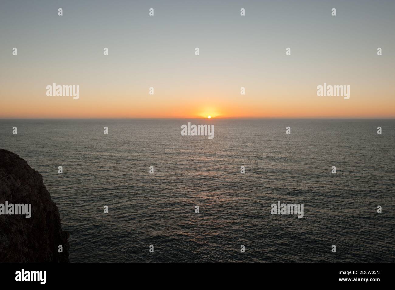 Sun setting over ocean in Sagres, Portugal in Summer Stock Photo