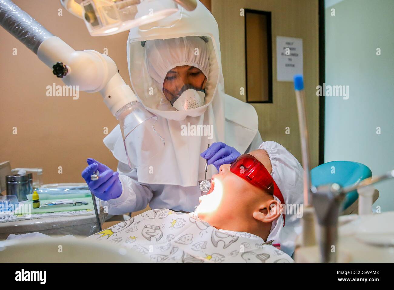 Manila, Philippines. 19th Oct, 2020. Dr. Maureen P. Ines-Manzano, a dentist, performs a dental brace adjustment on her patient while wearing a powered air-purifying respirator (PAPR) suit inside her clinic in Manila, the Philippines, on Oct. 19, 2020. Patients of Dr. Manzano has dubbed her the 'astronaut dentist' because of her resemblance to a spacewoman while wearing her PAPR suit to protect her patients and herself from the COVID-19 disease. Credit: Rouelle Umali/Xinhua/Alamy Live News Stock Photo
