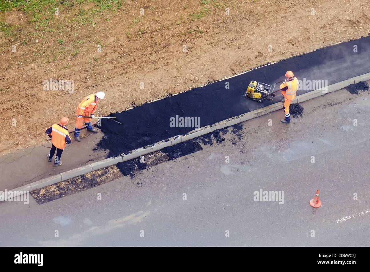 Road workers lay asphalt on the wet sidewalk during the rain, top view Stock Photo Alamy