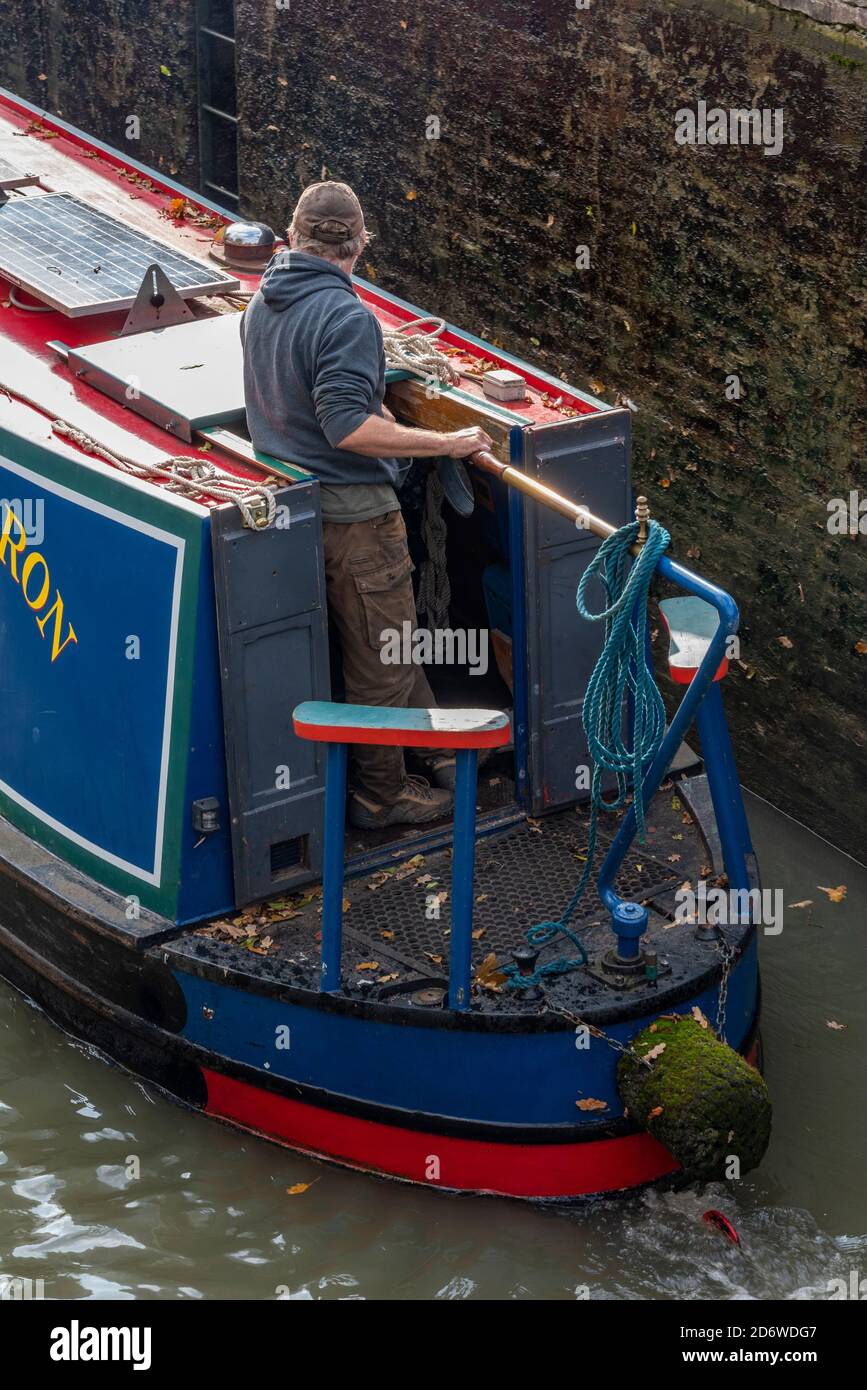 man at the helm or tiller of a traditional canal narrow boat ot barge on the grand union canal