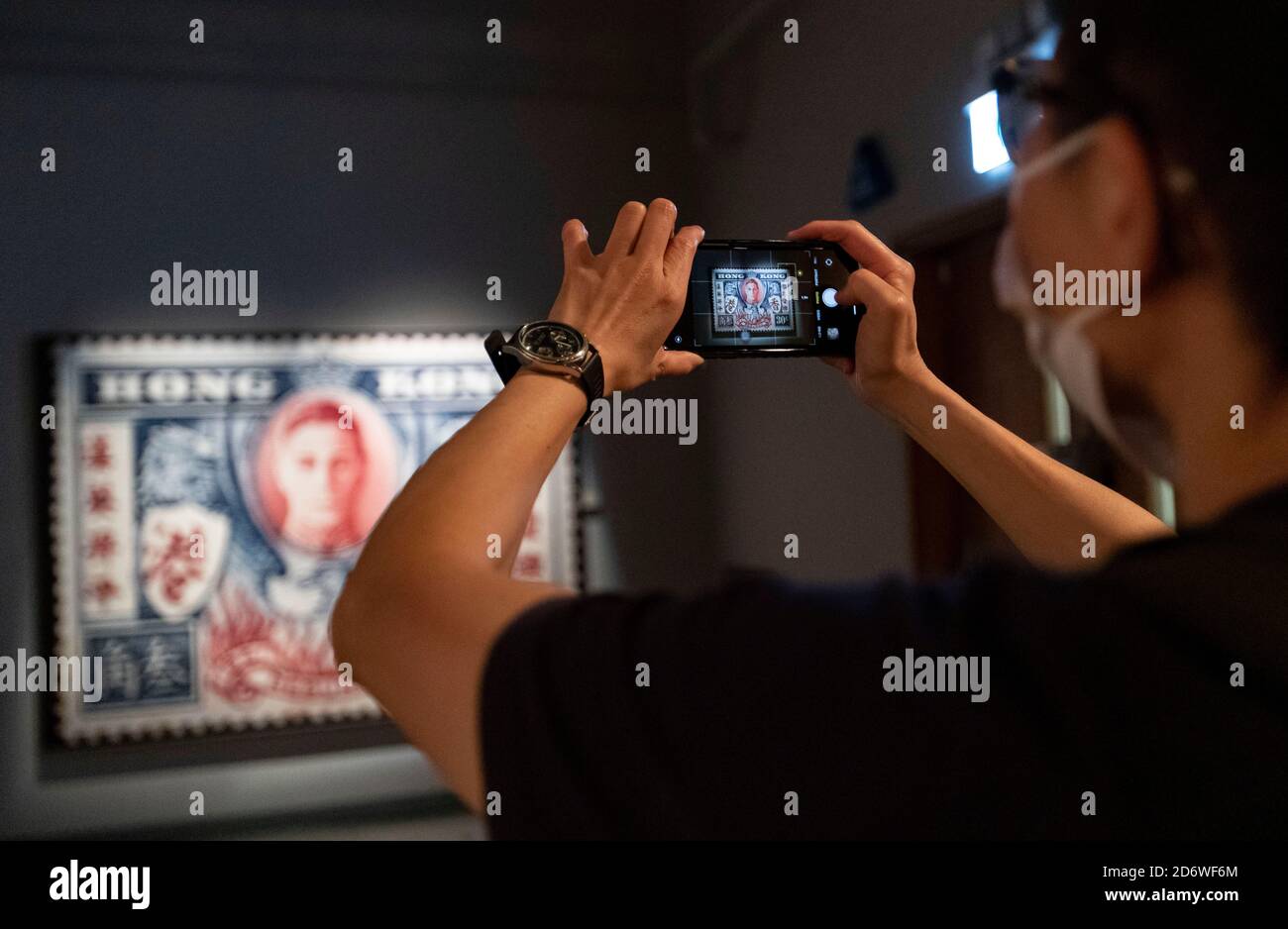A visitor takes a picture with his mobile phone of a stamp during colonial time at 'The Hong Kong Story' exhibition of the Hong Kong History Museum on its last day of opening before a two-year revamp.The permanent exhibition 'The Hong Kong Story' of the museum closed on 19 October 2020 for a major renovation for the next coming years creating a public concern whether the exhibitions and facts will remain untouched once it reopens. Stock Photo