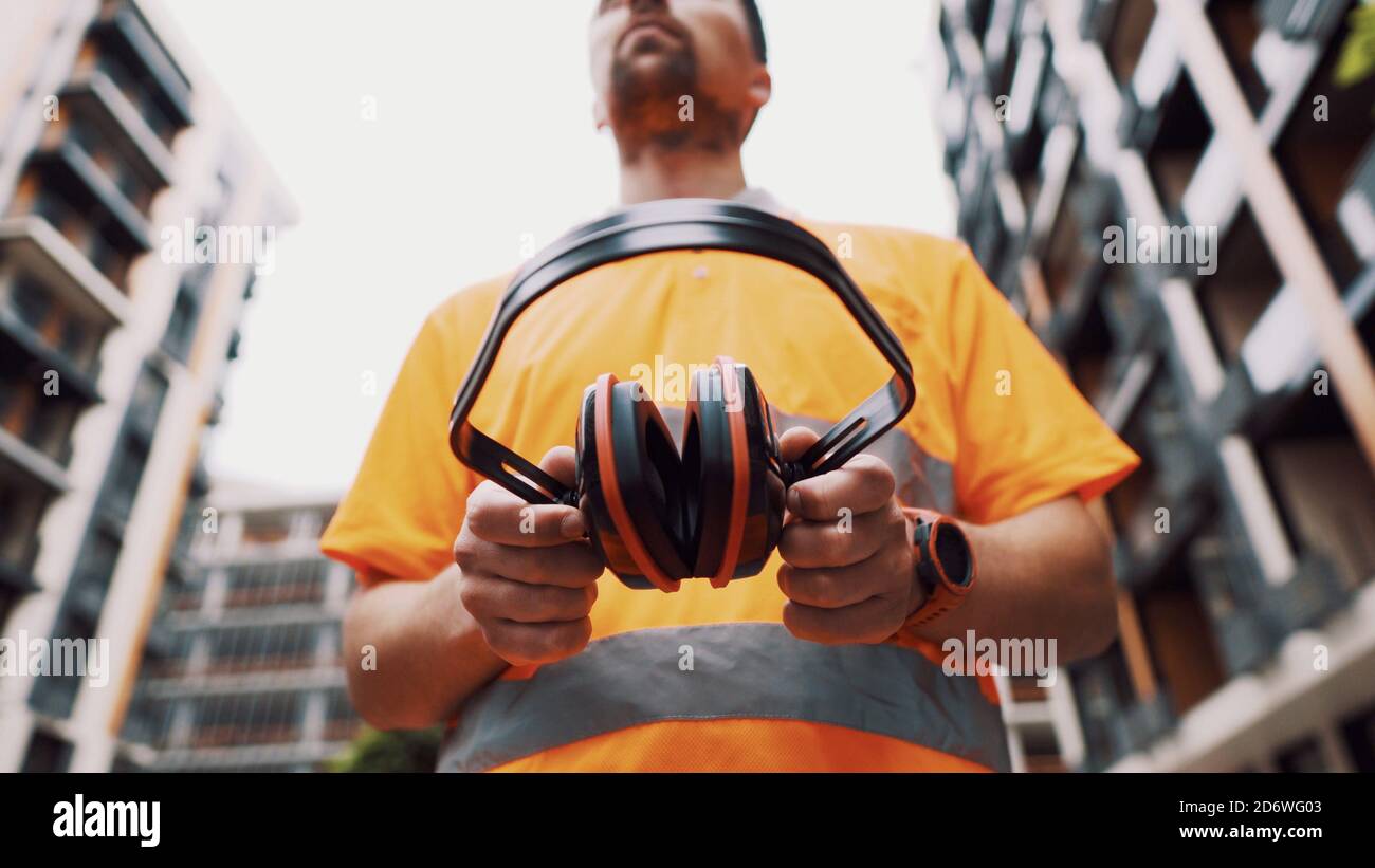Construction worker with ear muff working at construction site. Worker ...