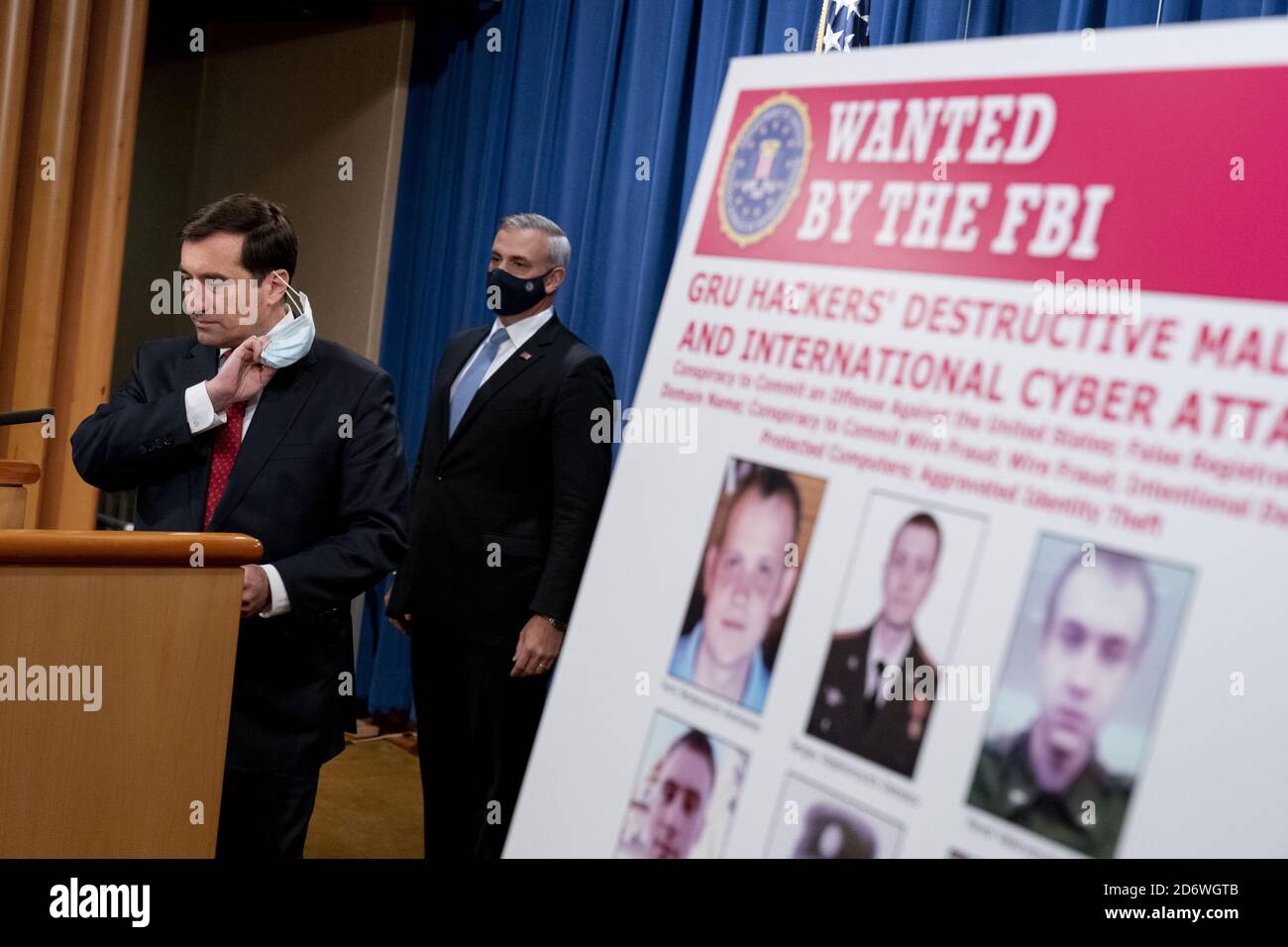 Washington, United States. 19th Oct, 2020. A poster showing six wanted Russian military intelligence officers is displayed as Assistant Attorney General for the National Security Division John Demers, left, takes the podium to speak at a news conference at the Department of Justice, Monday, October 19, 2020, in Washington, DC. Six Russian Military Intelligence agency (GRU) officers were charged by a Pittsburgh grand jury in regards to computer hacking. Pool Photo by Andrew Harnik/UPI Credit: UPI/Alamy Live News Stock Photo