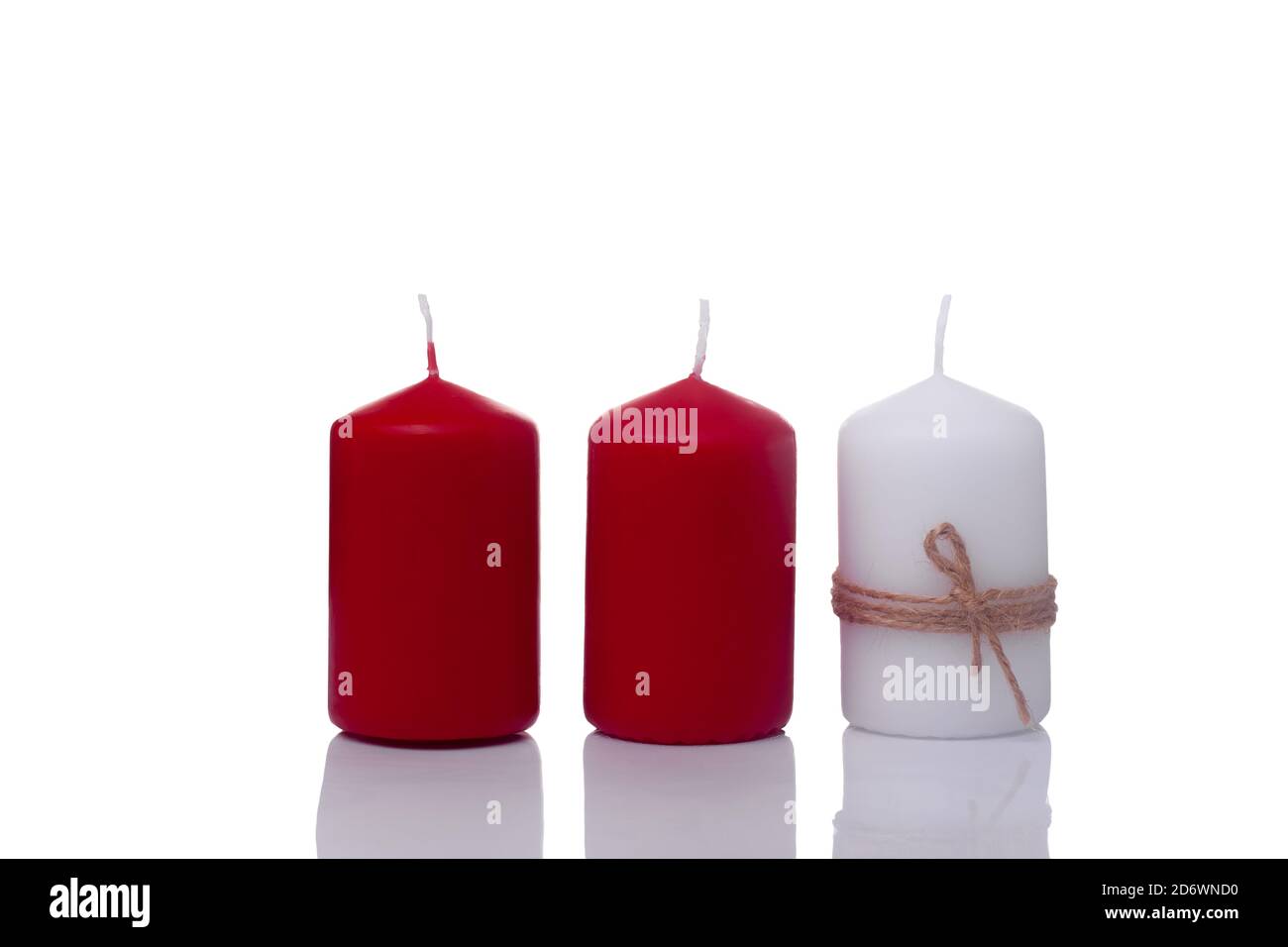 two red candles and one white candle in a jute rope, isolated on a