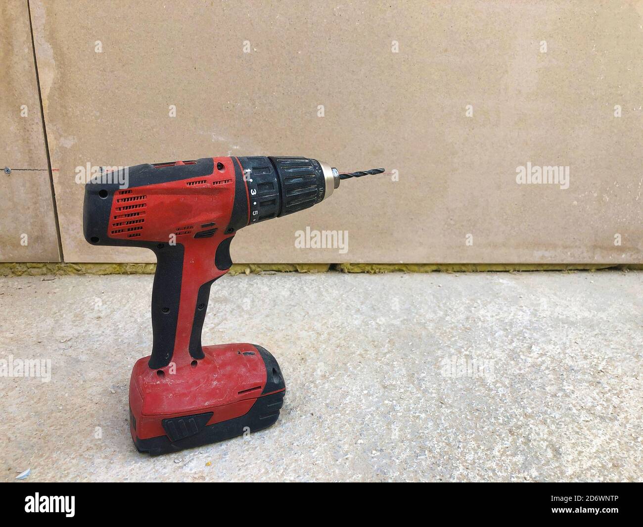 Cordless screwdriver on concrete surface against drywall. Electric power tools Stock Photo