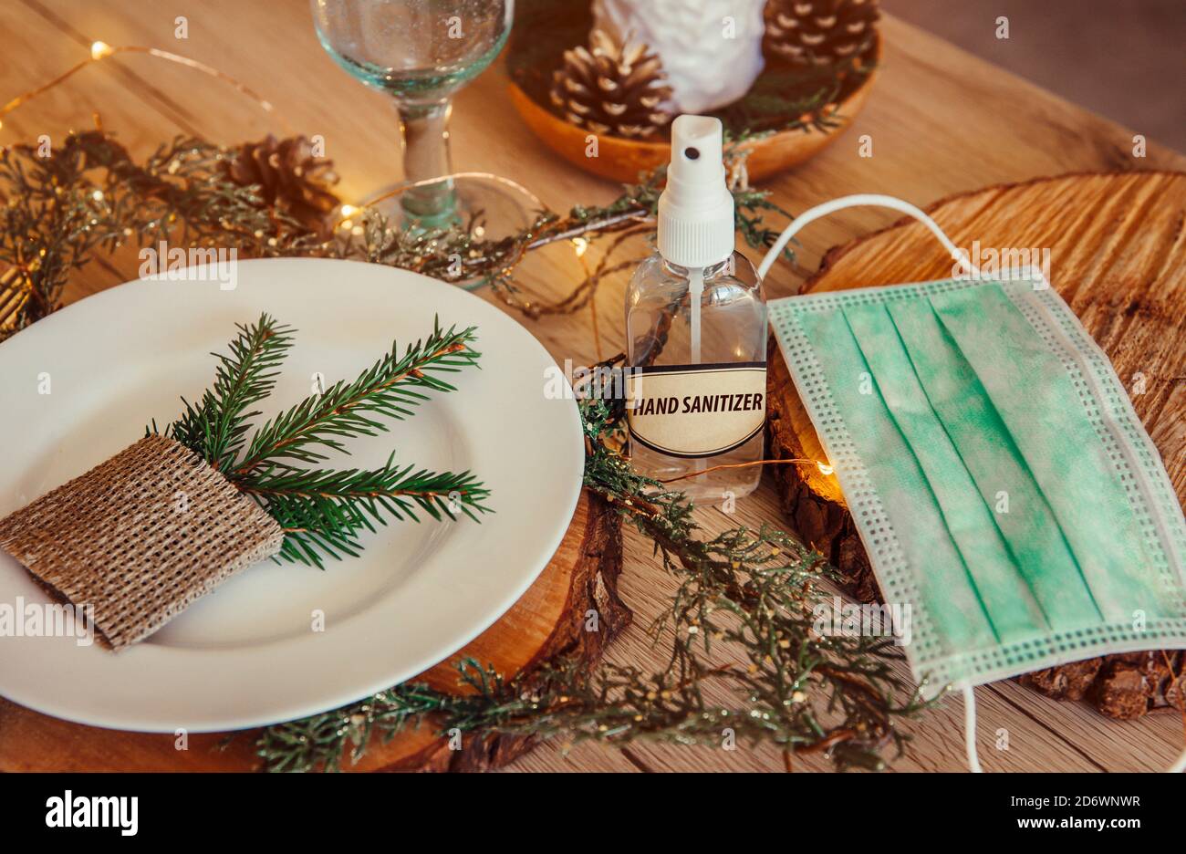 Christmas eve holiday party decorated table set with disposable medical mask and alcohol hand sanitizer bottle. Coronavirus (Covid 19) Stock Photo
