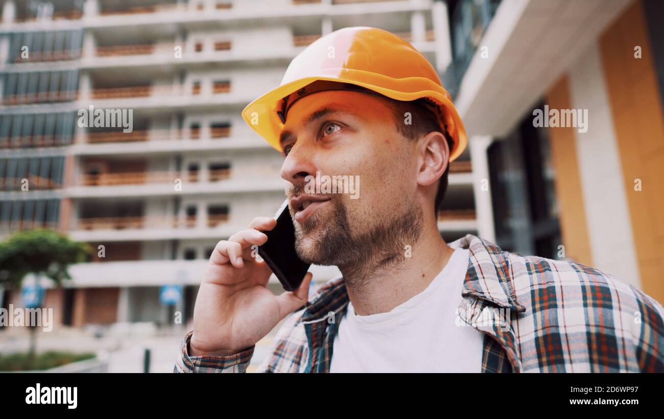 Contractor Making House Call Portrait of young handyman making call while standing at construction ...