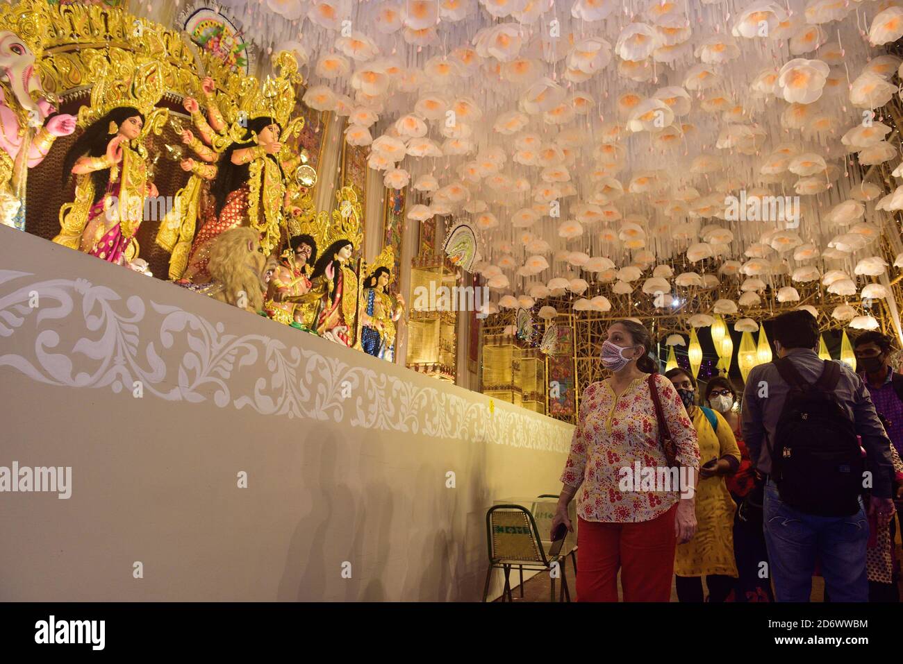 A woman wearing a facemask  is seen looking up at the idol of goddess Durga at Puja Pandal in Kolkata. Kolkata High Court ordered this evening that all puja pandals will be considered as No entry and containment zones. Only a selective number of Puja committee members will be allowed inside however with 5-meter distance from small pandals and 10-meters from big pandal barricade to control the huge number of people. Stock Photo