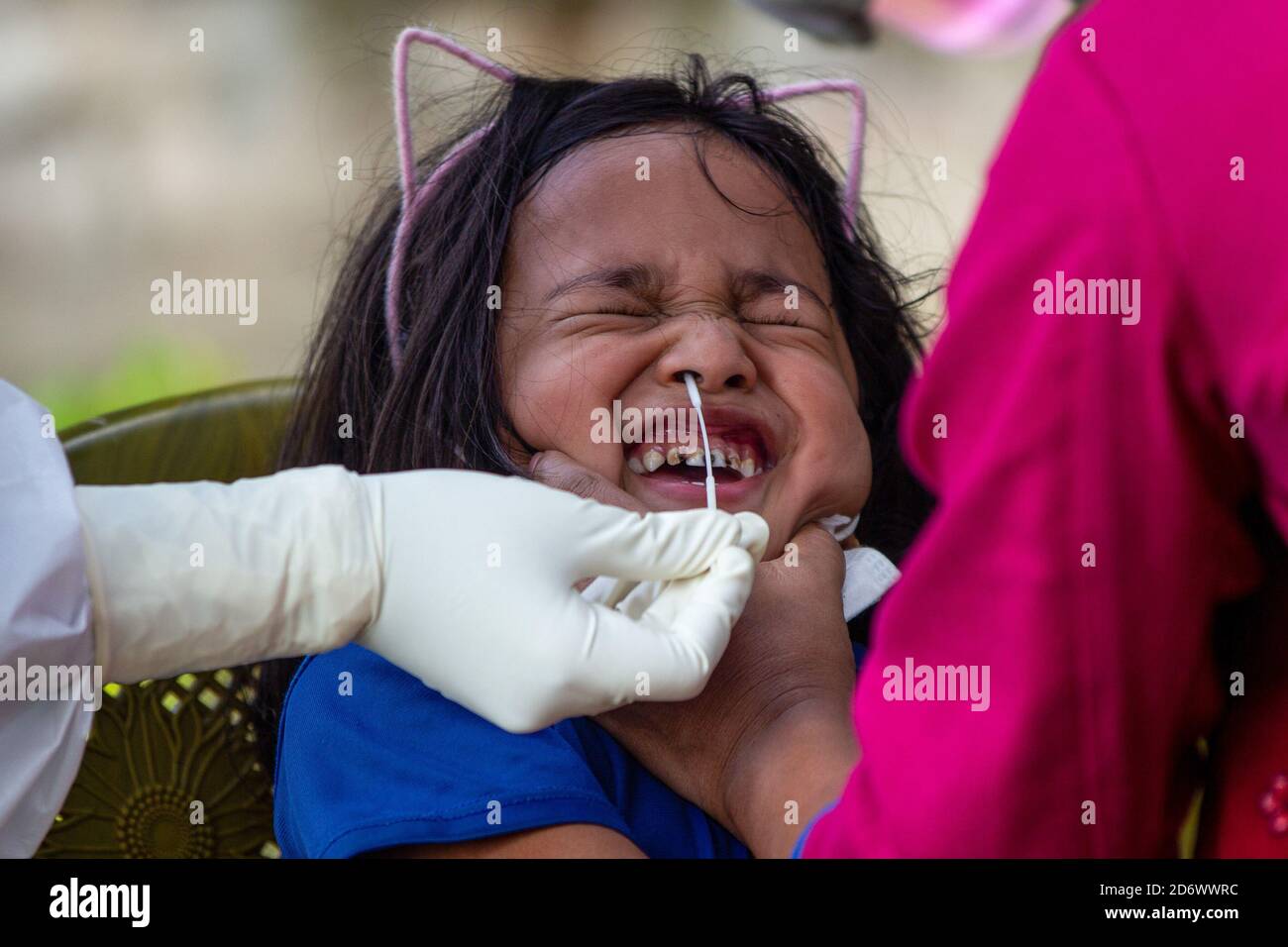 A child reacts while the healthcare worker takes a nasal swab sample at a COVID-19 testing center. The local government begins aggressive contact tracing of coronavirus patients and collect the swab for a COVID-19 test in order to control more transmission of the virus. Nepal has so far confirmed 1,36,036 Coronavirus positive cases 94,501 recovered and 757 deaths. Stock Photo