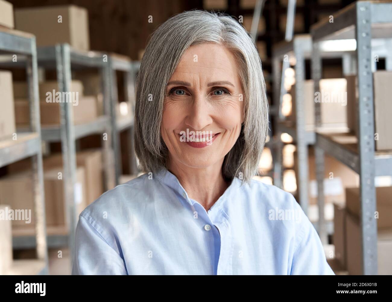 Happy mature female manager in delivery shipping warehouse, headshot portrait. Stock Photo