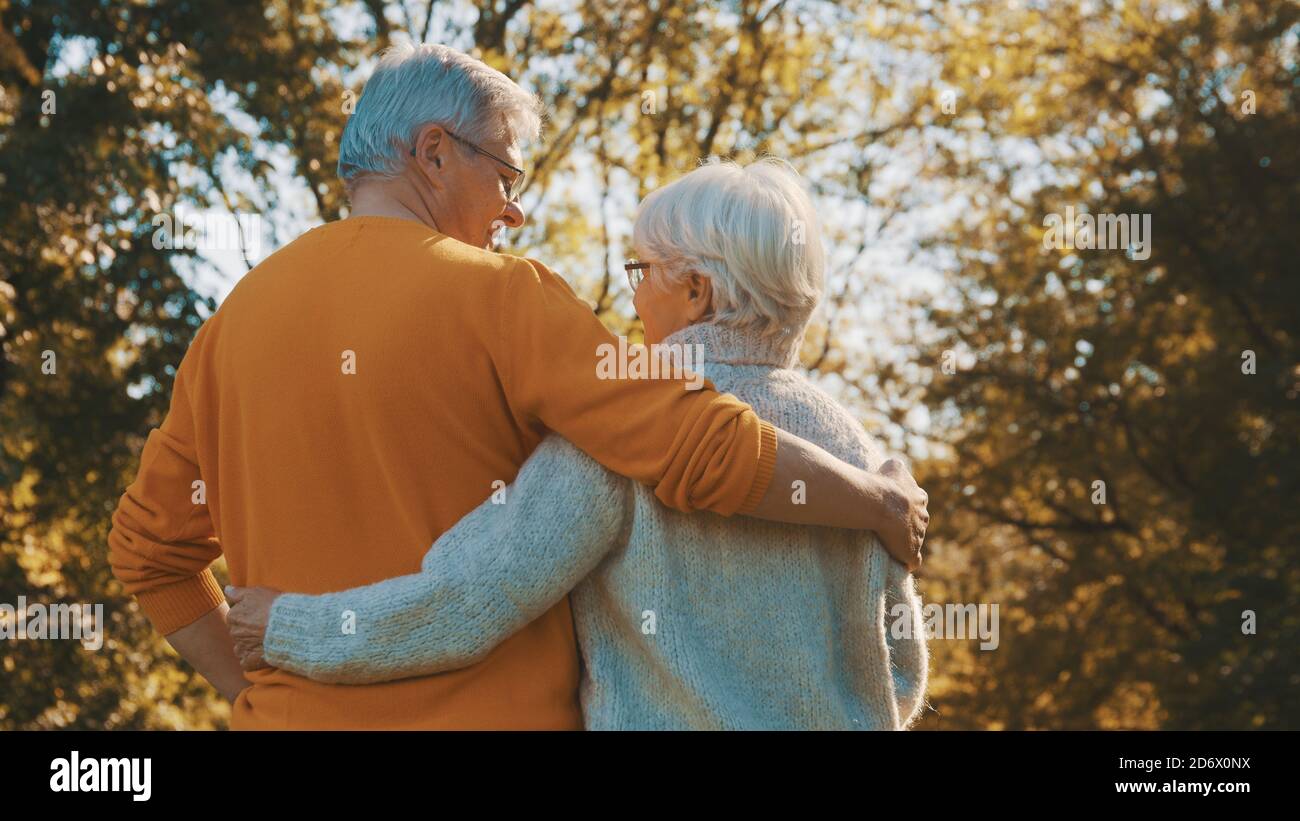 Happy old couple hugging in park. Senior man flirting with elderly woman. Romance at old age on autumn day. High quality photo Stock Photo