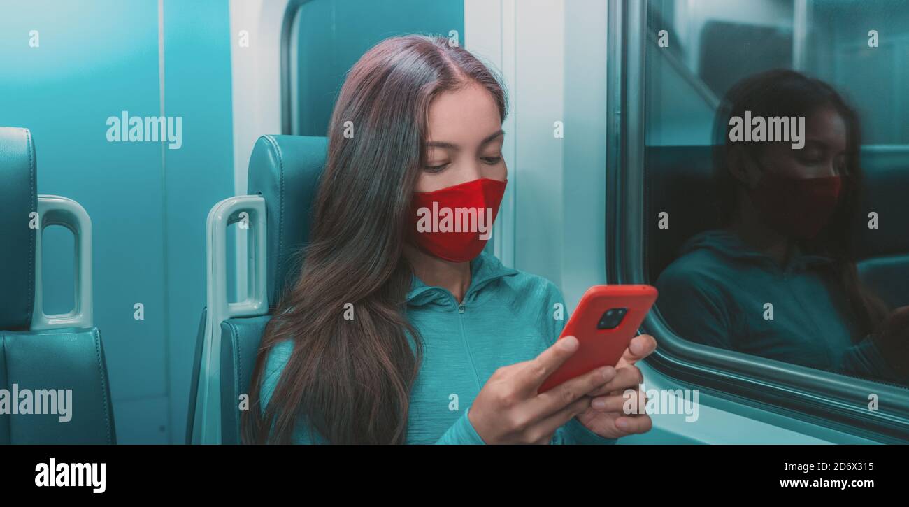 Face mask in public transport like train, bus. Woman passenger using mobile phone with face covering on subway commute ride at night Stock Photo