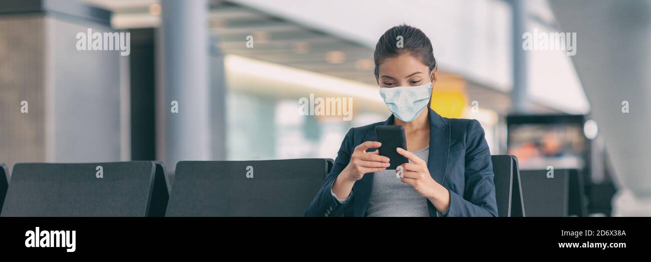 Mandatory face wear to cover mouth with mask protection. Asian woman using mobile phone app waiting flight departure in airport terminal banner Stock Photo