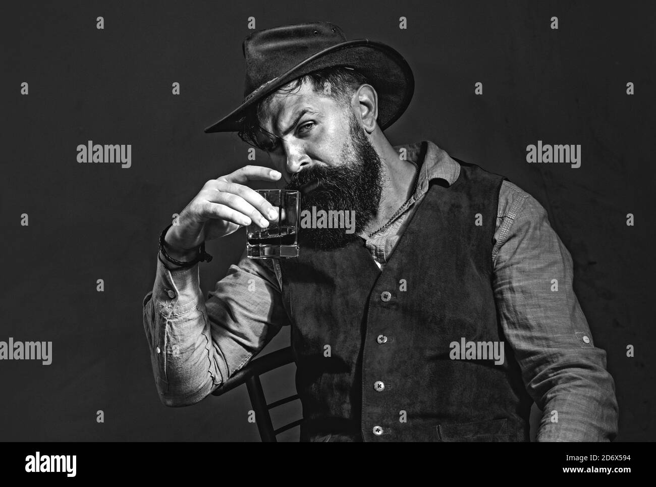 Stylish elegant bearded man Bartender holds whiskey glass. Luxury beverage concept. Fashionable man in white shirt and suspenders. Stock Photo