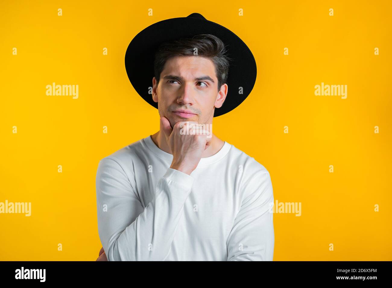 Thinking hipster man looking up and around on yellow background ...