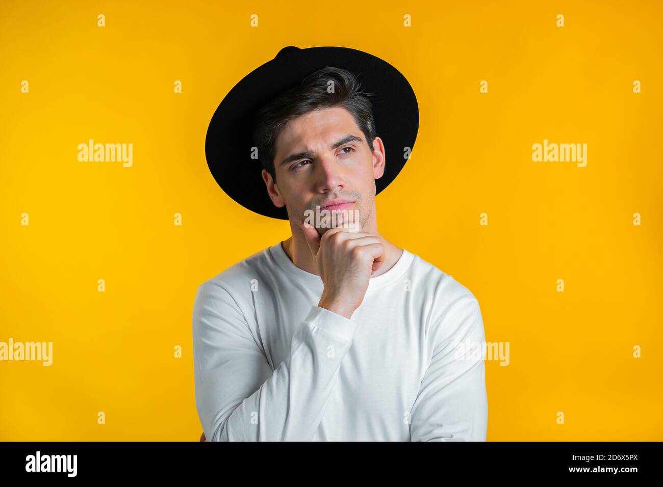 Thinking hipster man looking up and around on yellow background ...