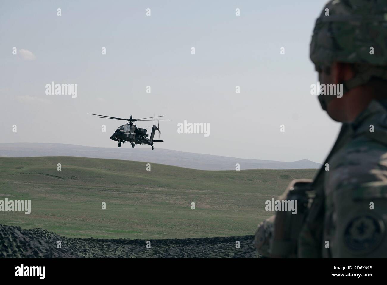 A U.S. AH-64 Apache helicopter flies by a U.S. Soldier, assigned to the 4th Squadron, 2d Cavalry Regiment, during a call to fire training with the 12th Combat Aviation Brigade at the Vaziani Training Area, Georgia, Sept. 14, 2020.     The 4/2 Soldiers successfully completed their training exercise at the Vaziani Training Area in Georgia from September 7th to September 18th. Designed to enhance regional partnerships and increase U.S. force readiness and interoperability, the exercise allows participants to conduct sniper and demo ranges, situational training exercises, live-fire exercises and c Stock Photo