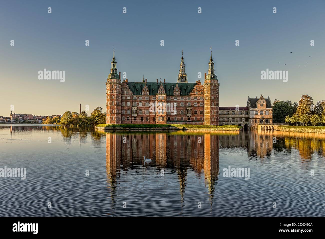 The Royal Frederiksborg castle glimmers in the sunshine and is reflected in the lake with a swimming swan, Hillerod, Denmark, October 17, 2020 Stock Photo