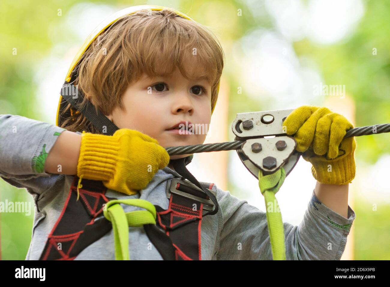 Children summer activities. Portrait of a beautiful kid on a rope park among trees. Every childhood matters. Active children. Roping park. Stock Photo
