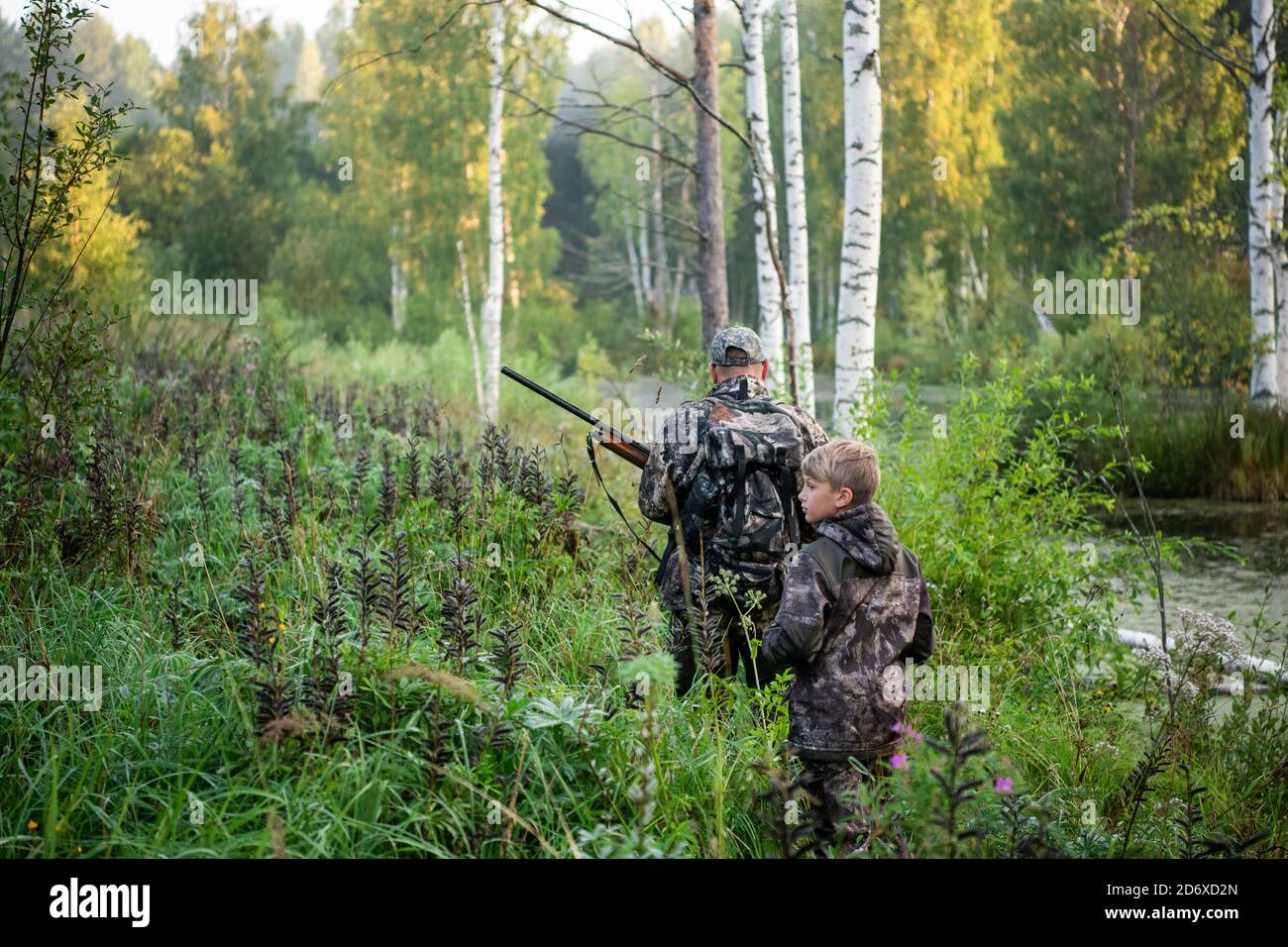Father's day. Father with gun showing something to son while hunting on