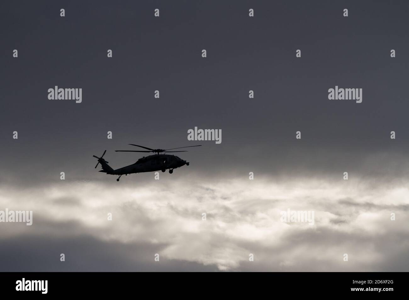 A silhouetted Sikorsky SH-60 Seahawk helicopter, of Carrier Air Wing Five, flying near Naval Air Facility, Atsugi airbase, Kanagawa, Japan. Stock Photo