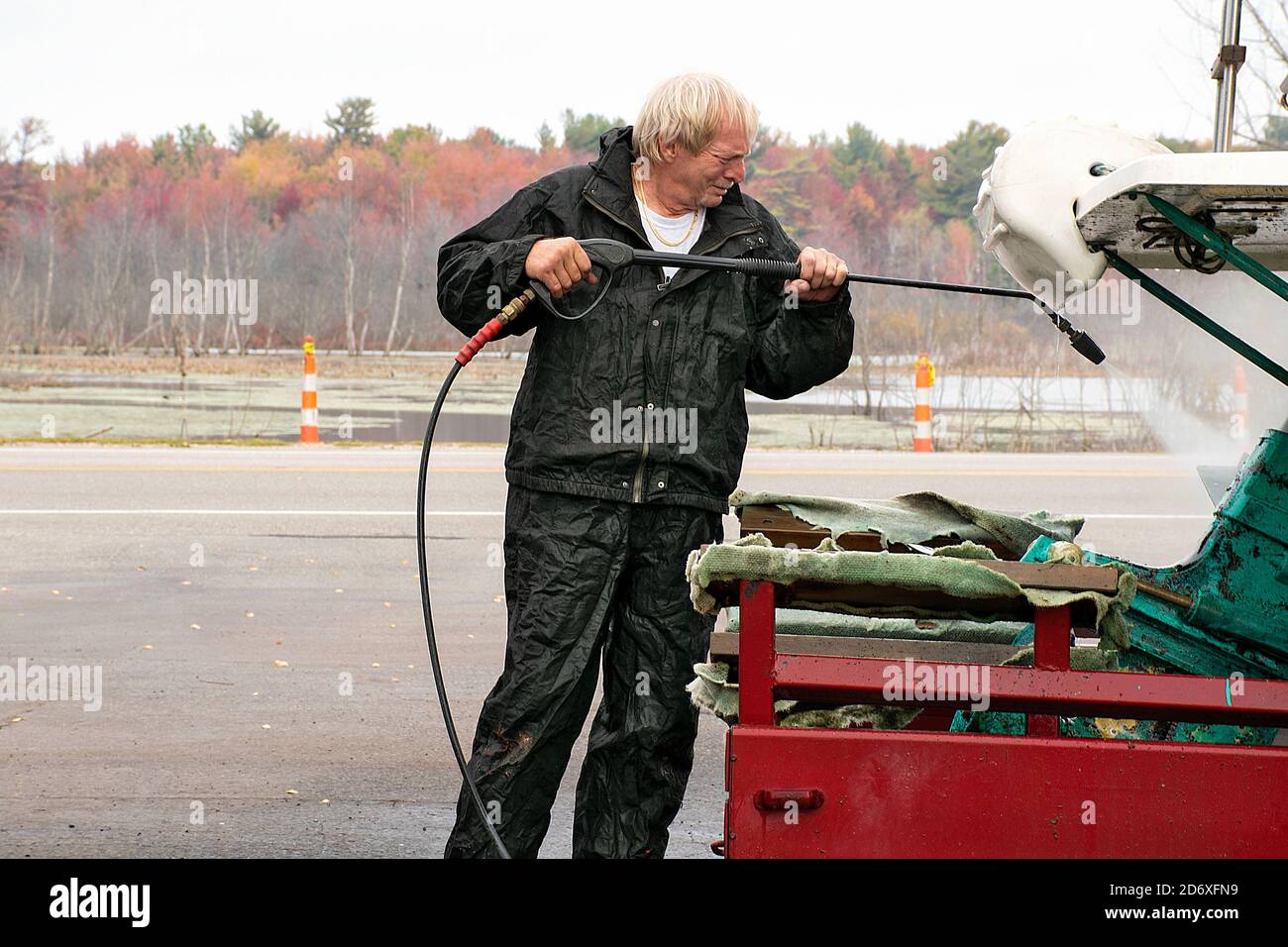 Caucasian man using pressure washer on dirty boat stern Stock Photo