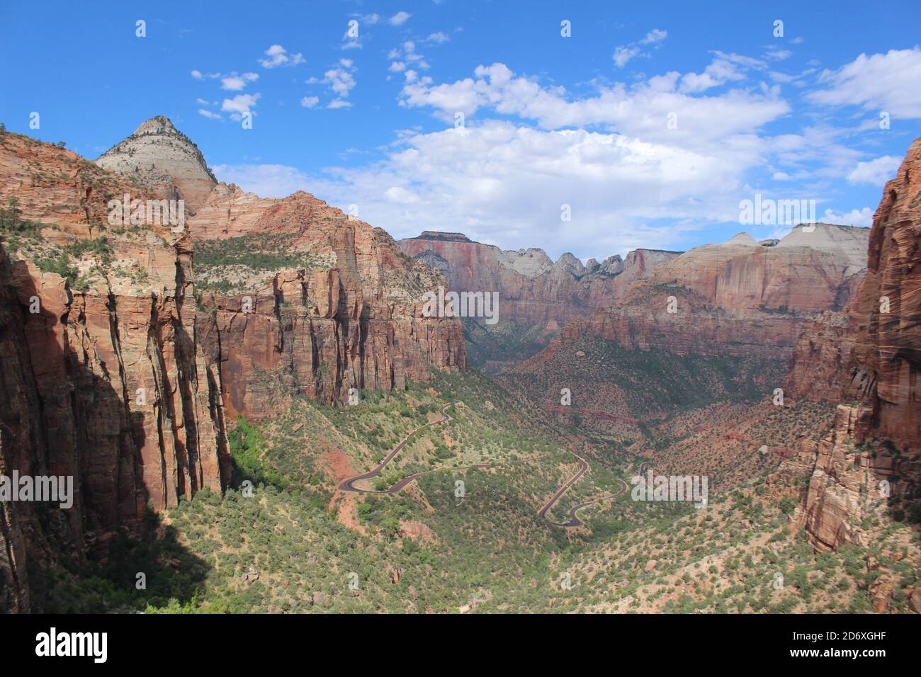 Panoramic view of a wide canyon in Zion National Park, Utah showing towering sandstone cliffs and a lush green canyon floor Stock Photo