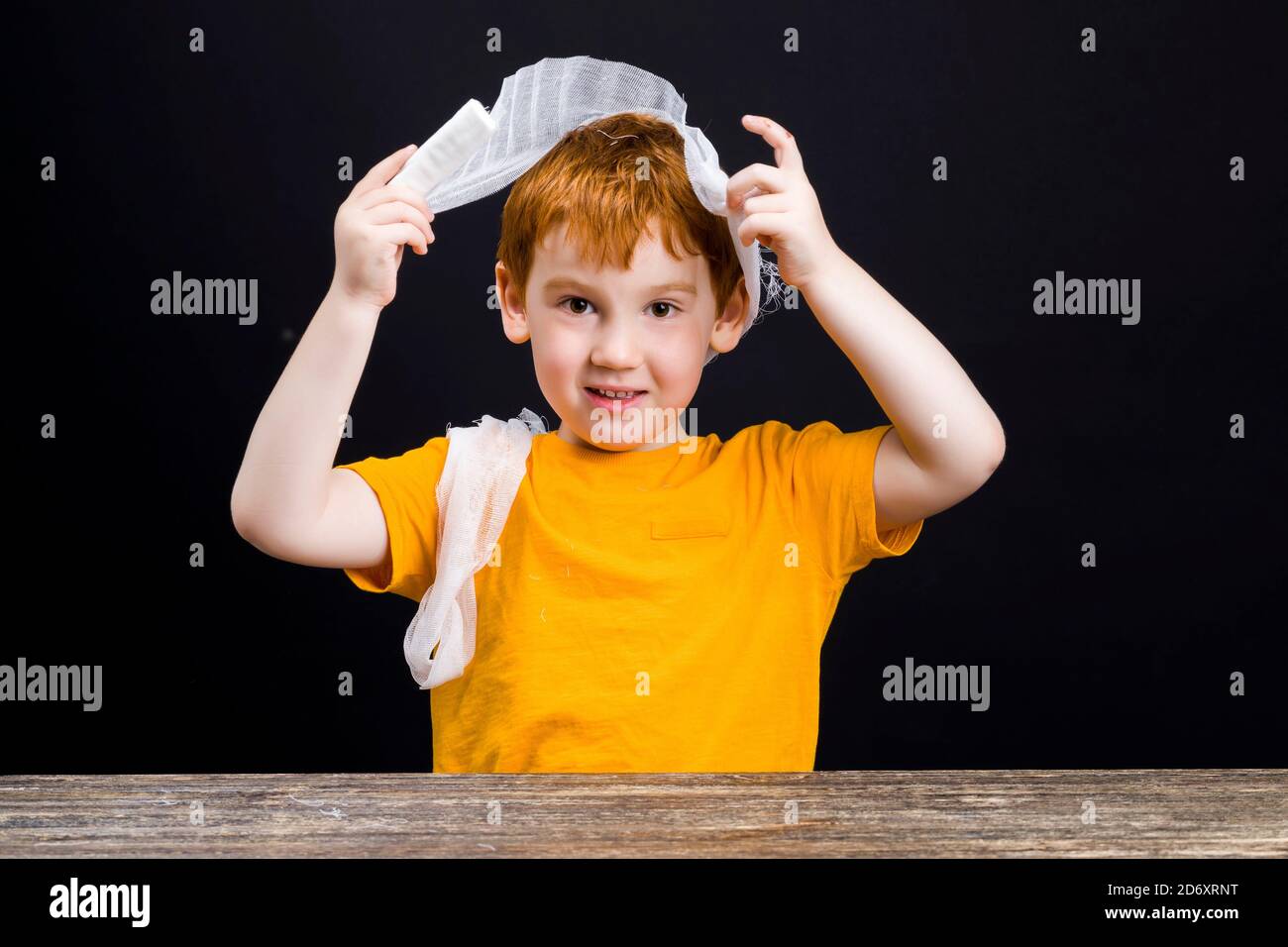 a beautiful boy with red hair with a damaged head bandages himself with a medical bandage, a boy with medical equipment during self-treatment, closeup Stock Photo