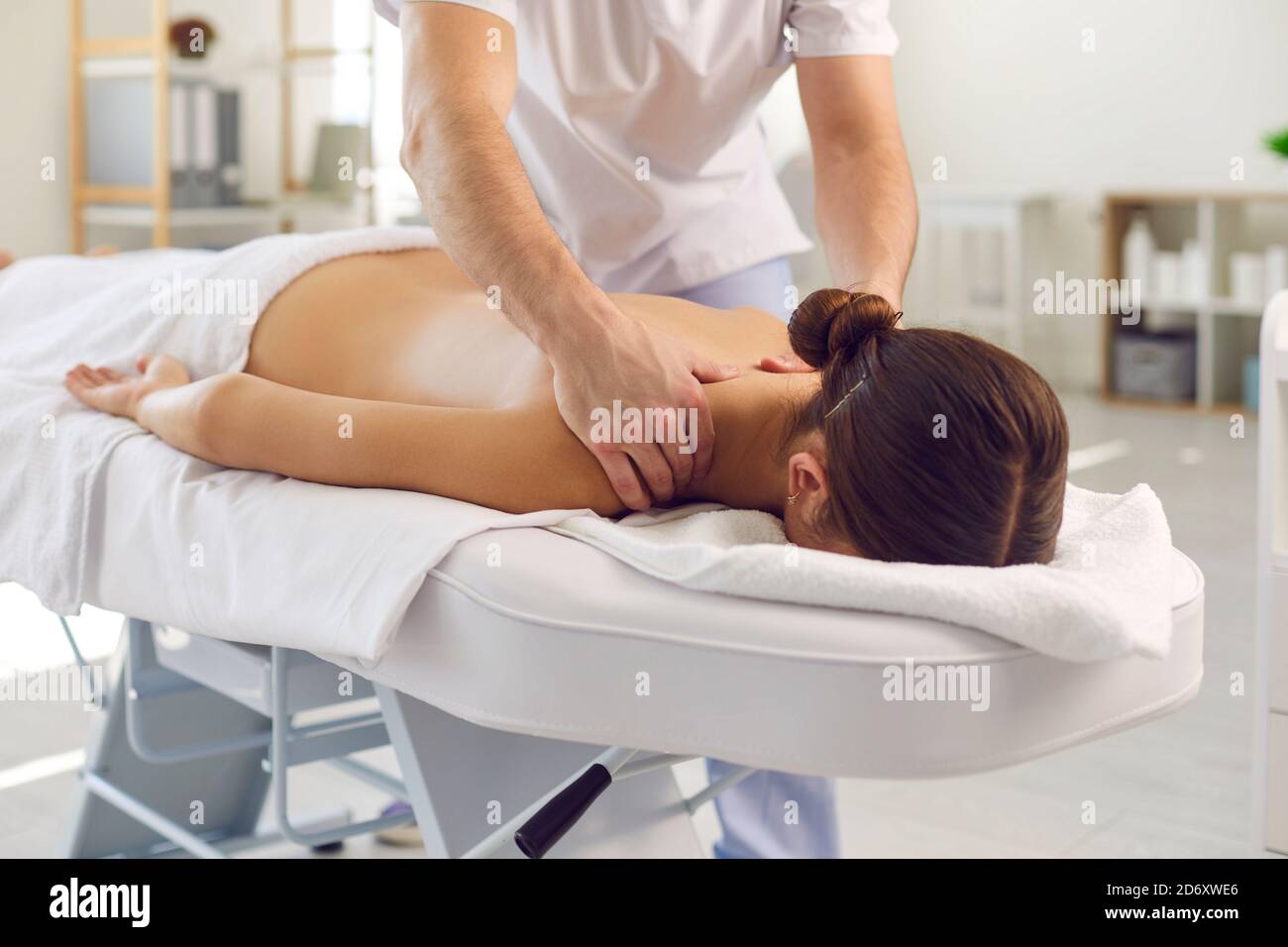 Masseur or manual therapist doing professional remedial body massage for young woman Stock Photo