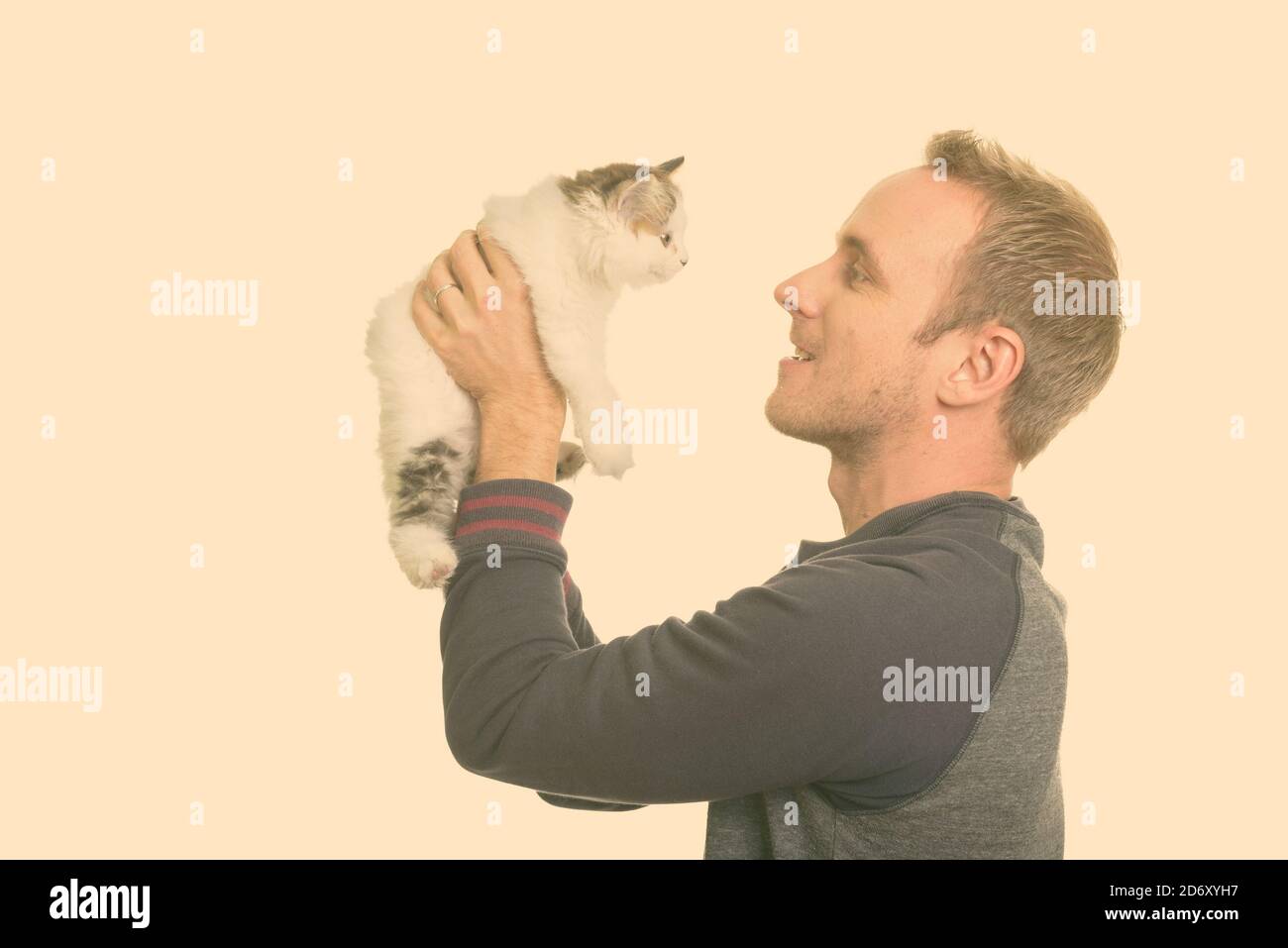 Profile view of happy handsome Caucasian man holding cute kitten Stock Photo