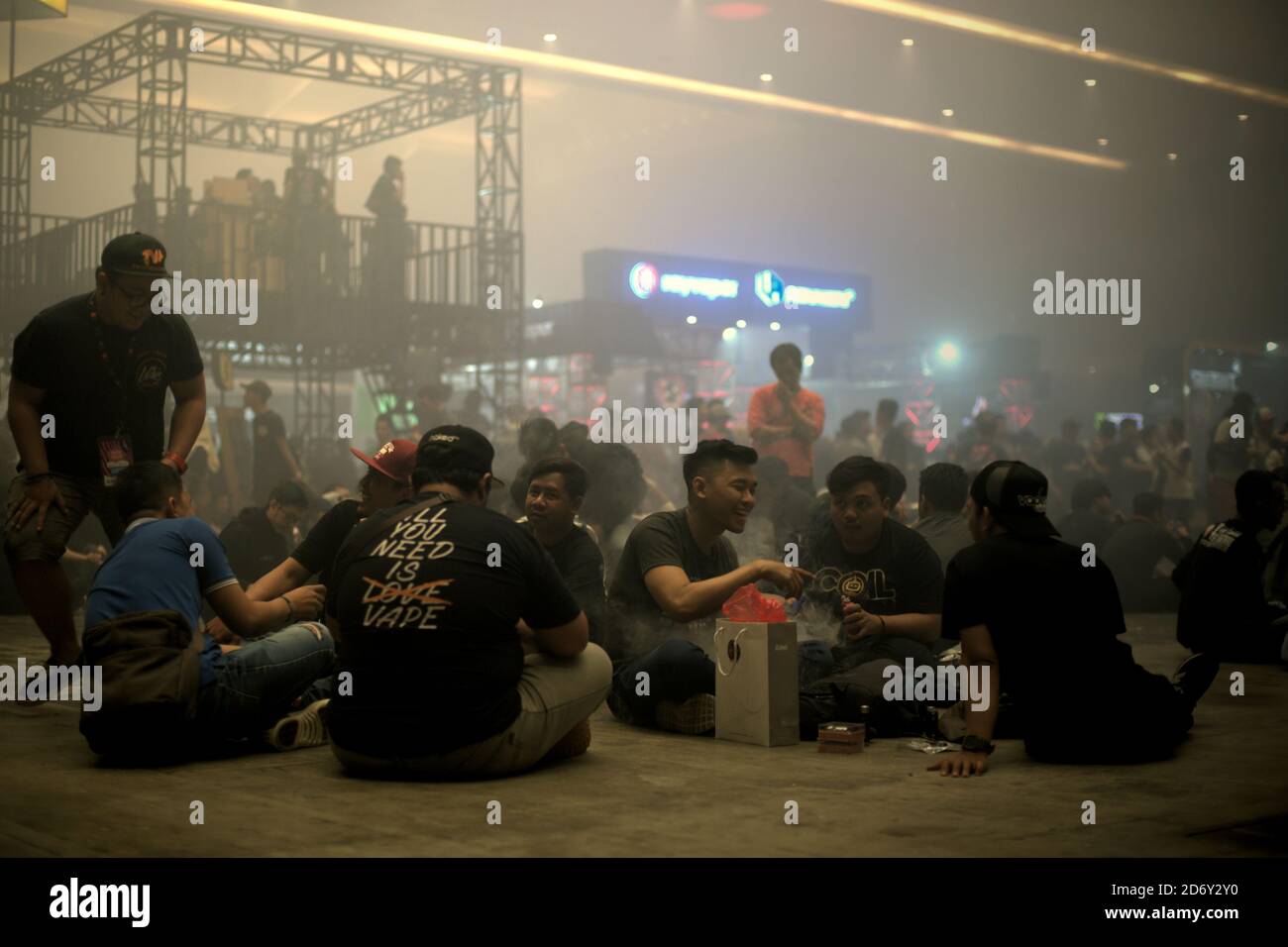 Some groups of visitors getting a rest while the others are participating in quiz and games at main stage area during the annual Vape Fair in Jakarta, Indonesia. Stock Photo