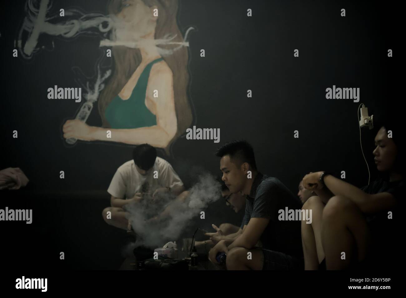 Vaping enthusiasts having leisure time with meals and e-cigarette vapours inside a vape cafe in Banten province, Indonesia. Stock Photo