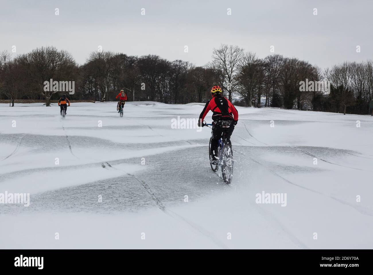 Mountain bikers cycling across a snowy landscape Stock Photo