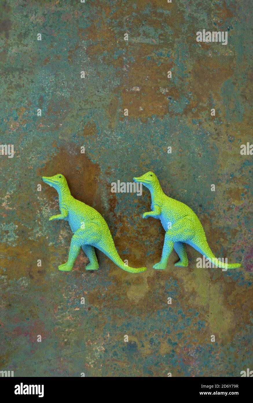 Two models of dinosaurs Tyrannosaurus with blue bodies and lime green backs walking in line Stock Photo