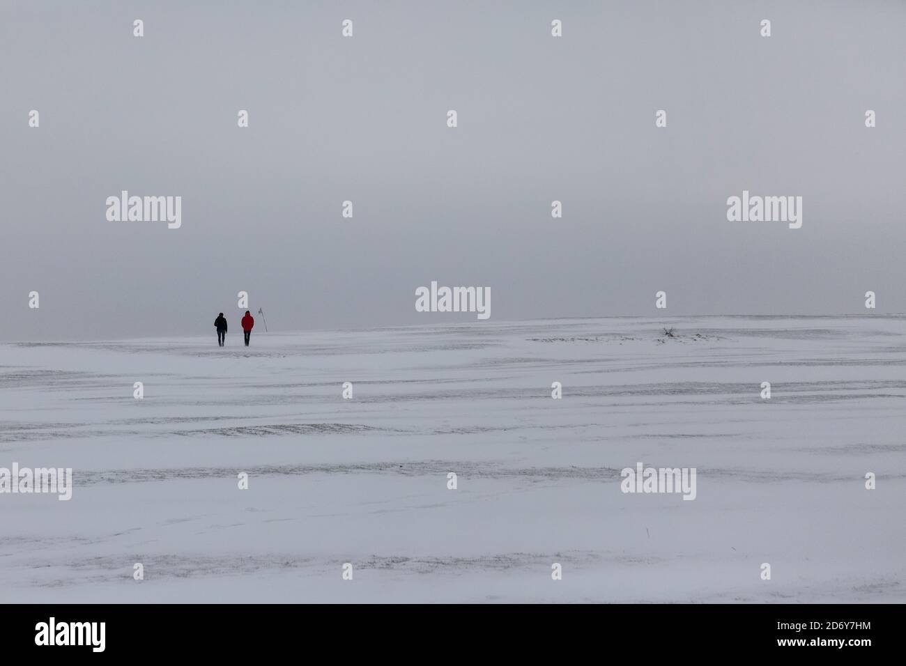 Two walkers in the distance walking across a snow covered landscape in the UK after the beast from the east snowstorm Stock Photo