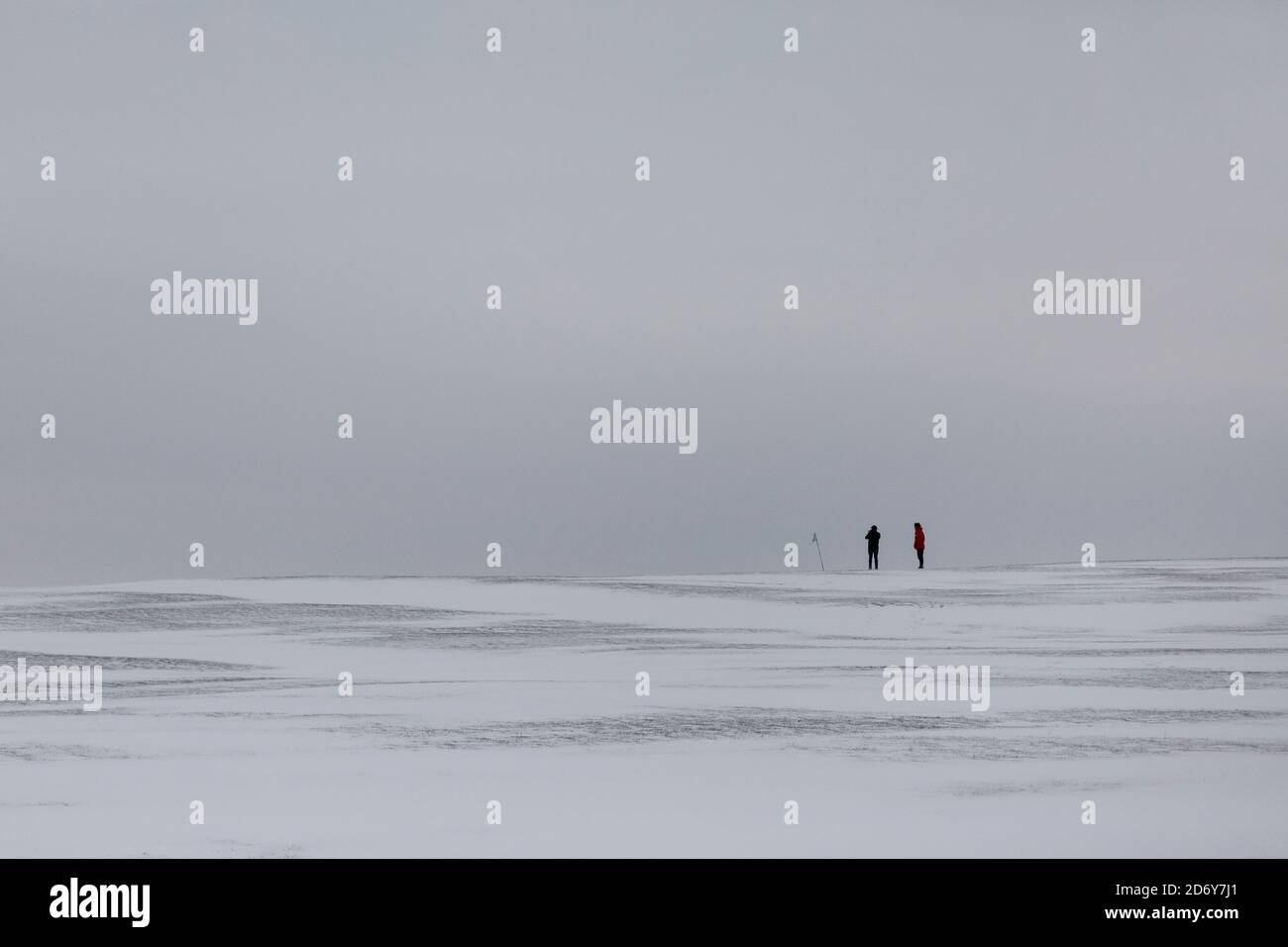 Two walkers in the distance walking across a snow covered landscape in the UK after the beast from the east snowstorm Stock Photo