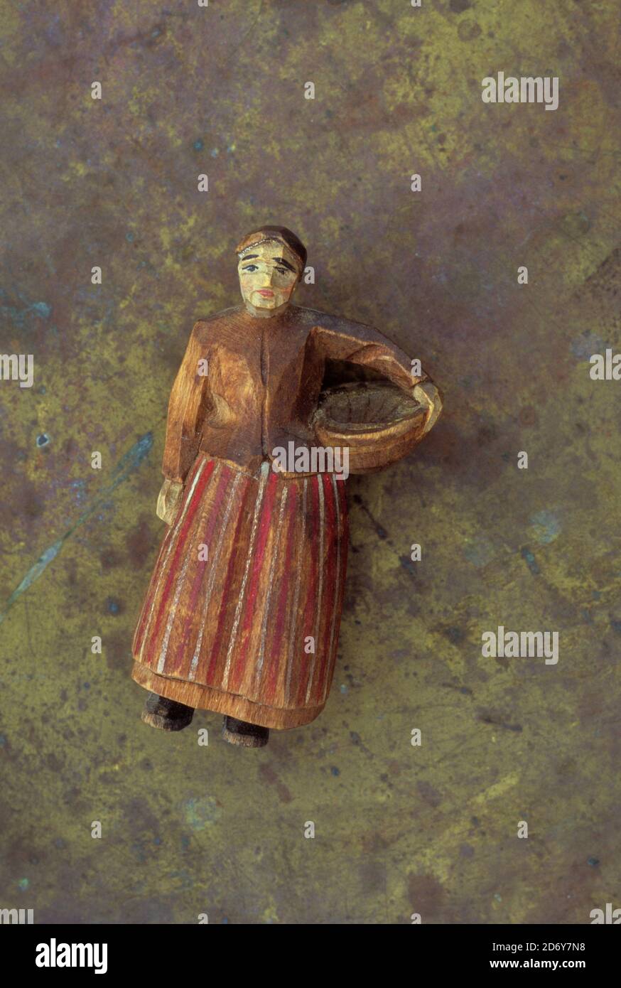 Vintage naive carved and painted wooden model of farm woman in long skirt holding bowl for feeding chickens or sowing seeds Stock Photo