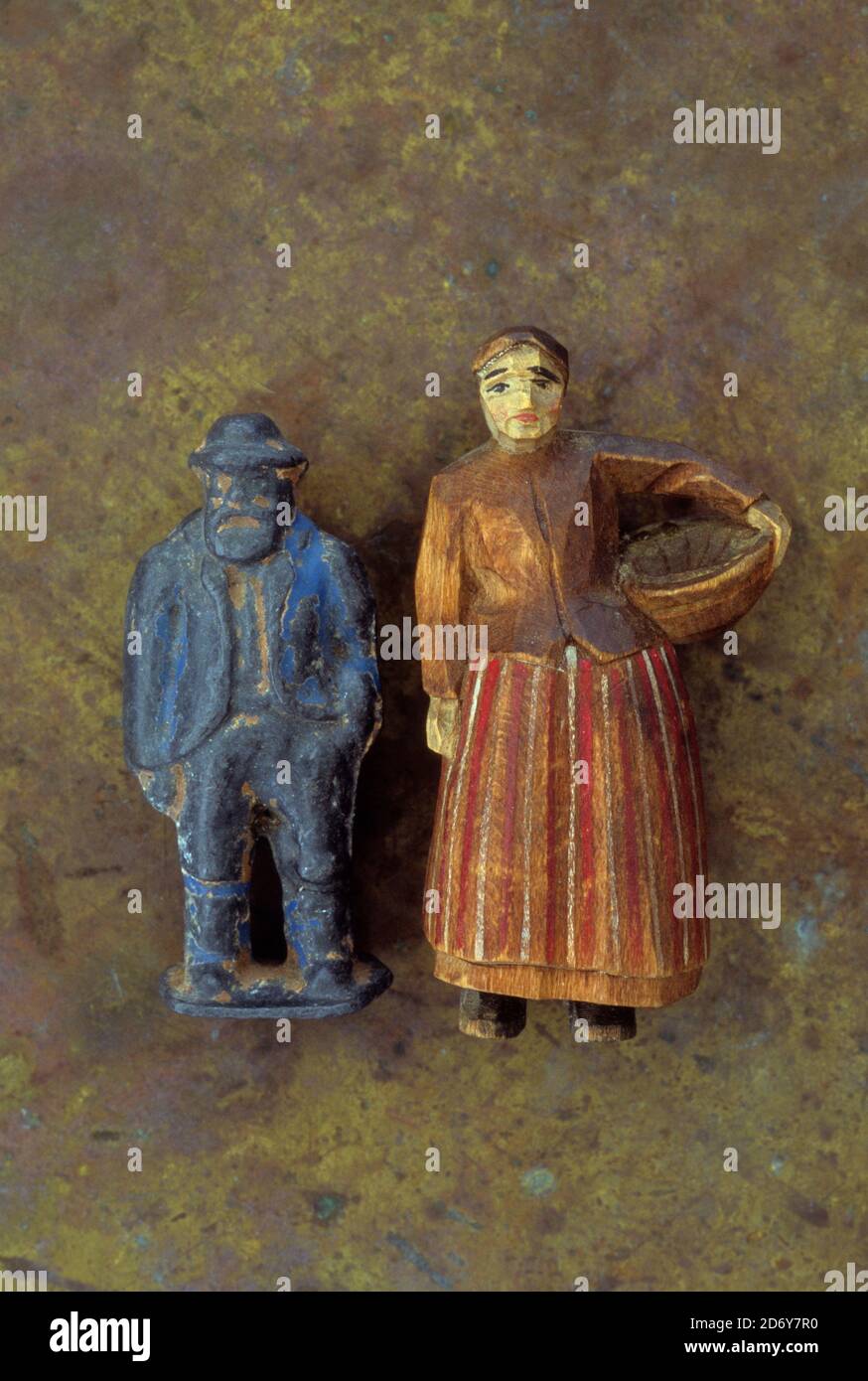 Vintage naive carved and painted wooden model of farm woman in long skirt holding bowl for feeding chickens standing next to grumpy farmer Stock Photo