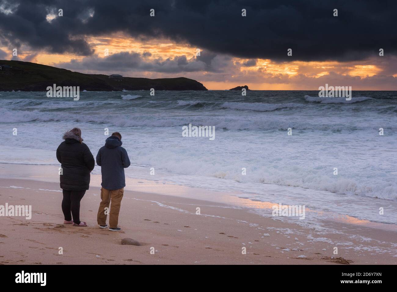 A couple standing on Fistral Beach watching a spectacular sunset in Newquay in Cornwall. Stock Photo