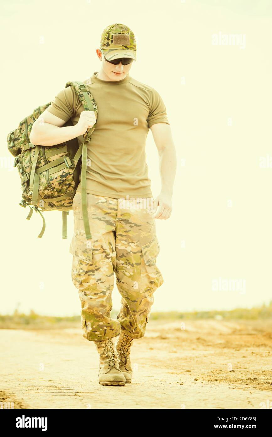 solider walking on dusty road with backpack Stock Photo