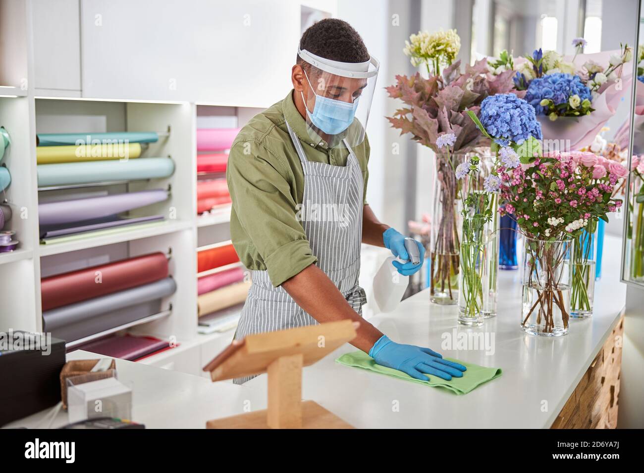 Shop assistant doing desinfection in flower shop Stock Photo