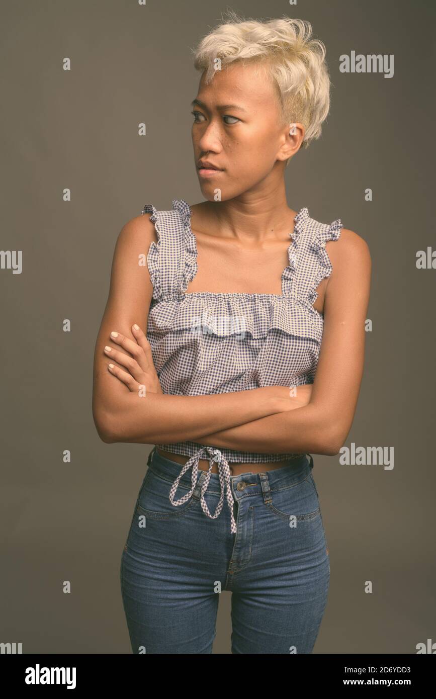 Young beautiful rebellious woman with short hair against gray background Stock Photo