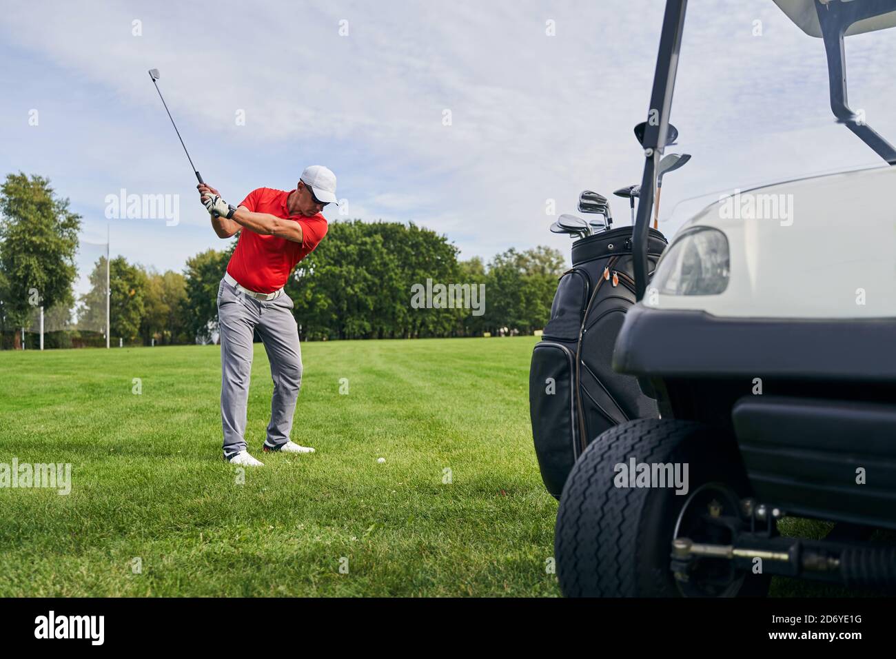 Serious golfer in a cap striking the ball Stock Photo