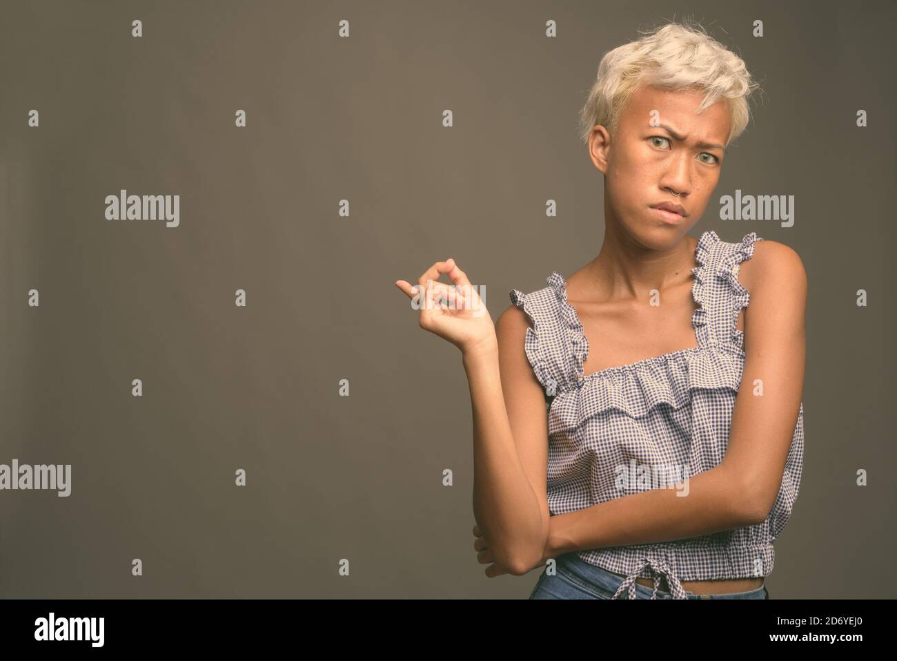 Young beautiful rebellious woman with short hair against gray background Stock Photo