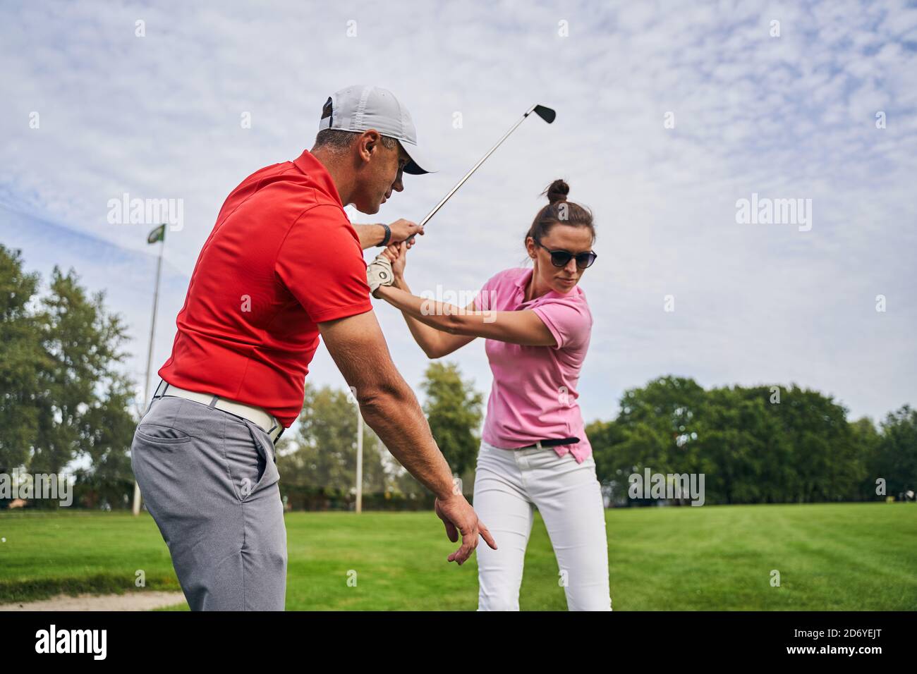 Golfer mastering a swing technique assisted by her coach Stock Photo