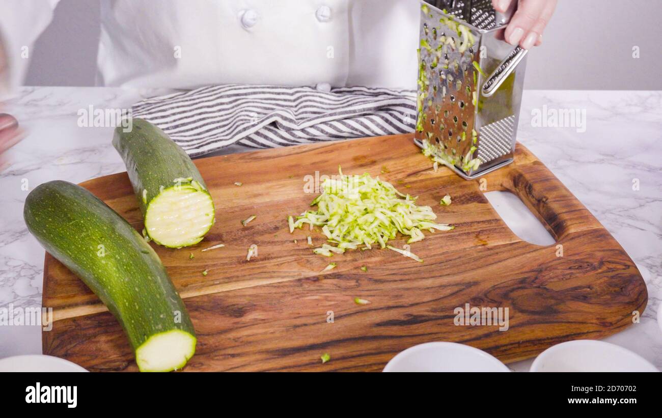 Step by step. Shredding organic zucchini to make zucchini cakes Stock