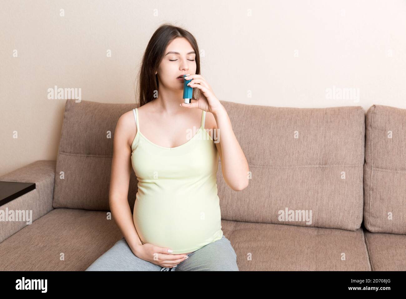 pregnant woman using asthma inhaler during attack for being healthy on